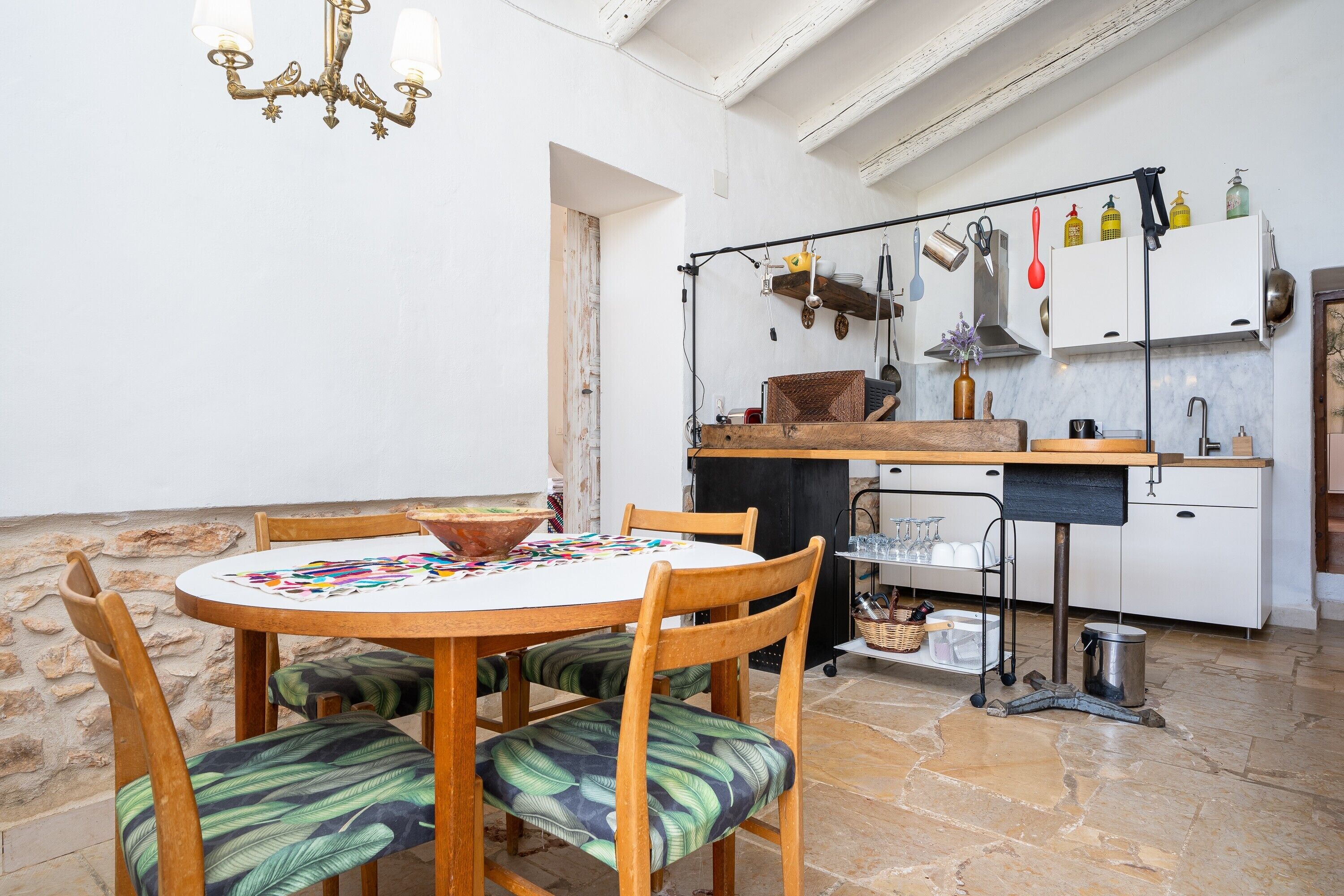 Una cocina con comedor, paredes de piedra y una araña.