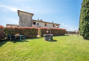 A stone building with a garden, a table with chairs, and a fountain.