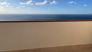 Un balcon avec vue sur la mer et un ciel dégagé.