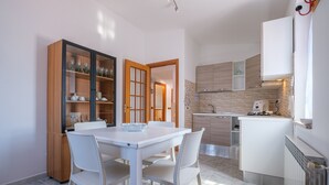 Une cuisine moderne avec des meubles blancs, une table à manger avec des chaises et un four encastré.