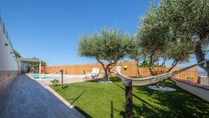 Un jardin avec une piscine, un hamac et une clôture en bois.