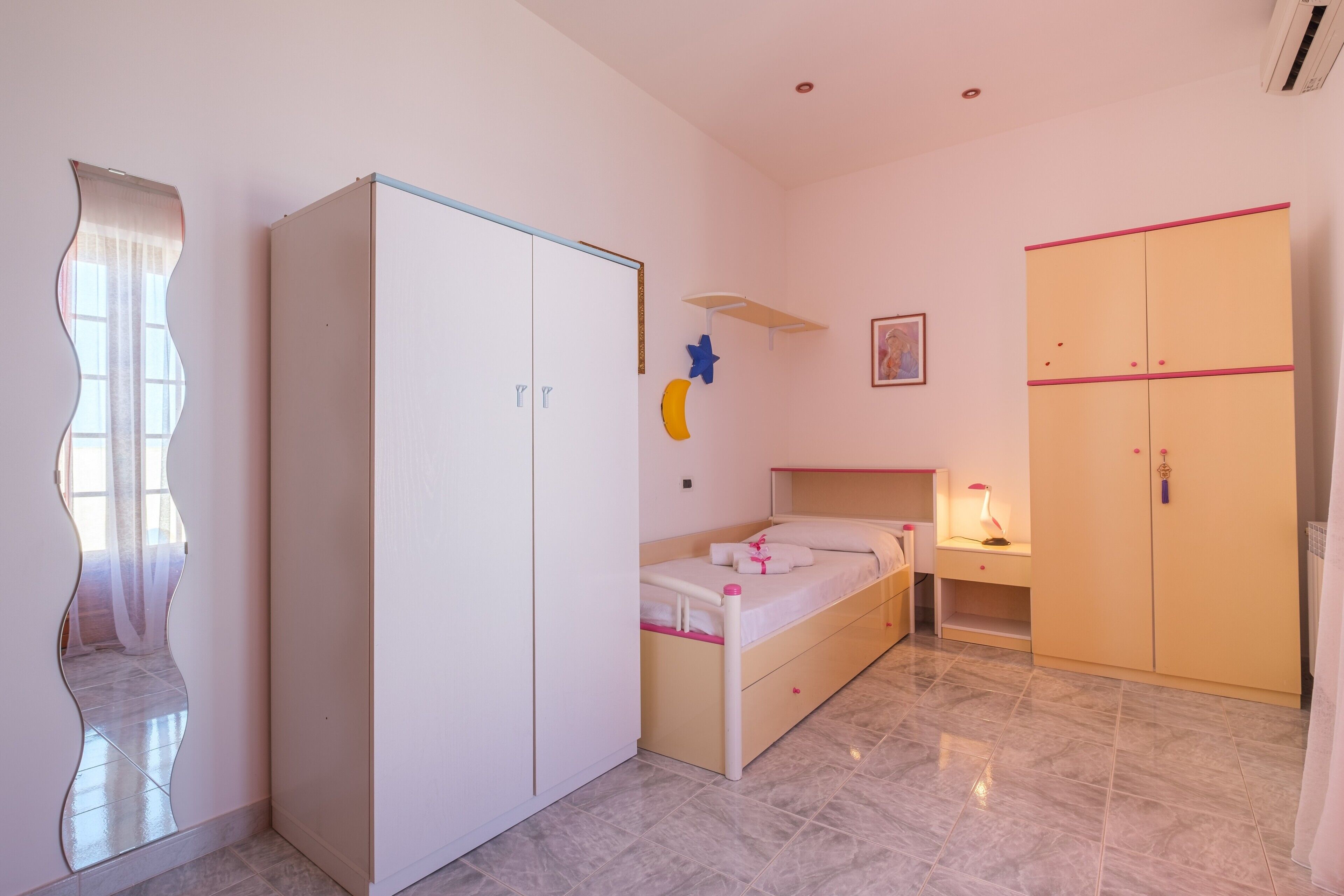 Une chambre à coucher comprenant un lit, une armoire, une table de chevet et un miroir.