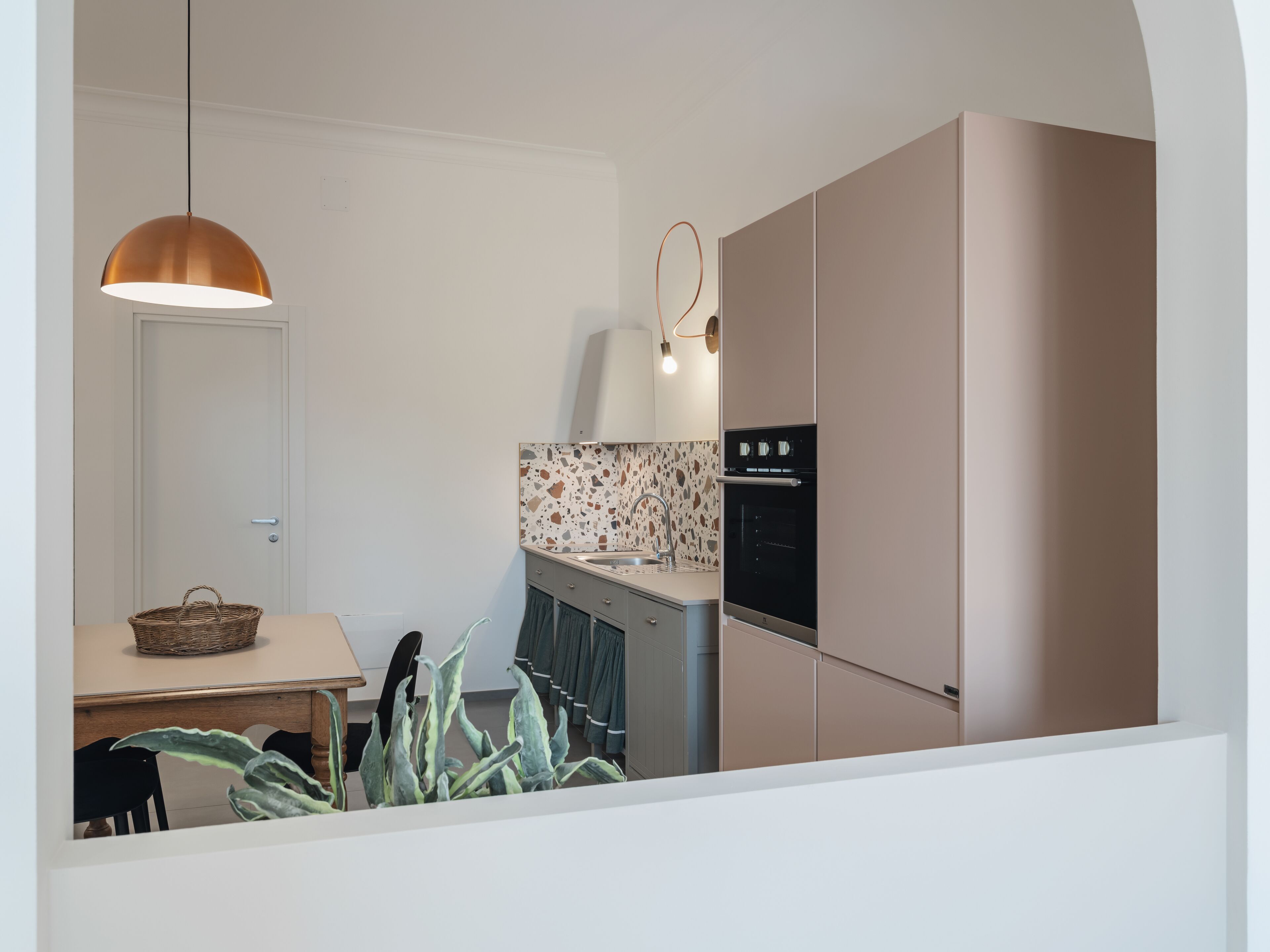 A modern kitchen with a built-in oven, a hanging pendant light, and a backsplash with a speckled pattern.