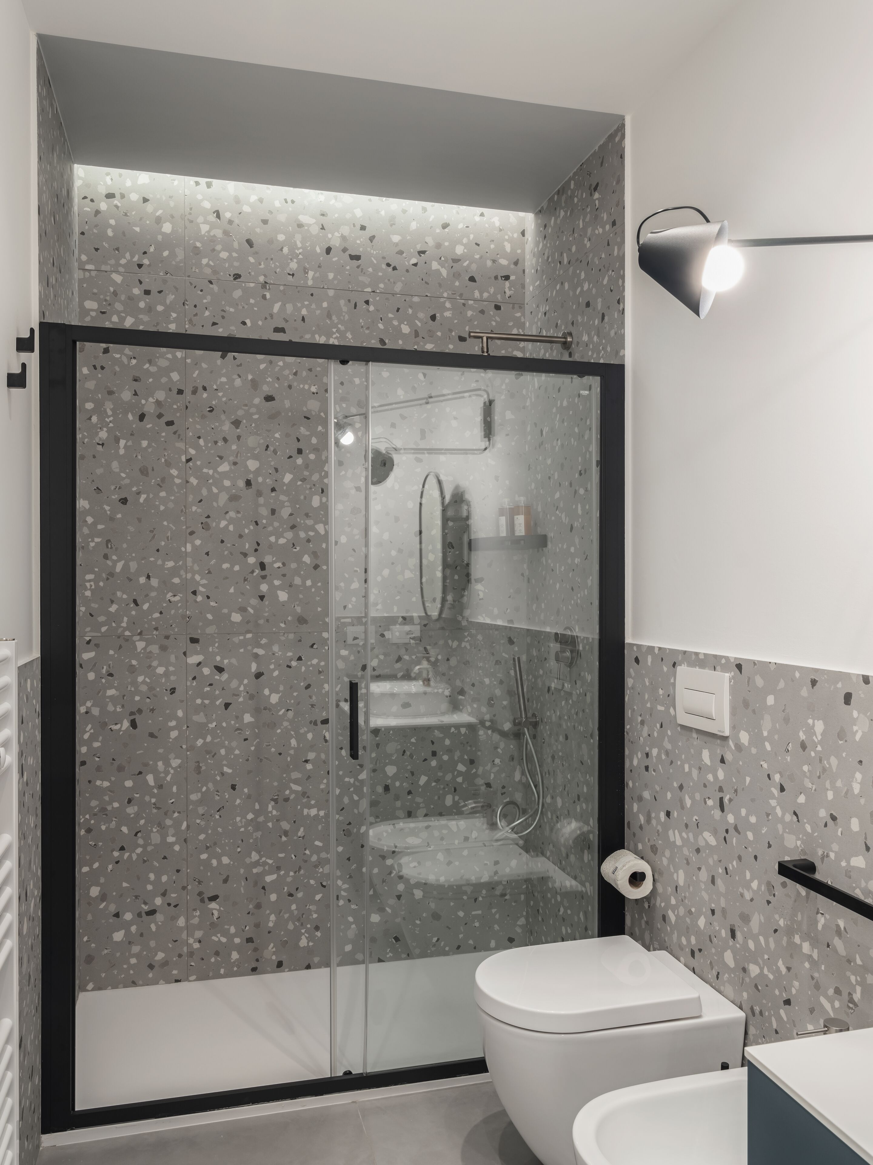 Ein modernes Badezimmer mit einer gläsernen Duschkabine, einer weißen Toilette und einem wandmontierten Waschbecken.