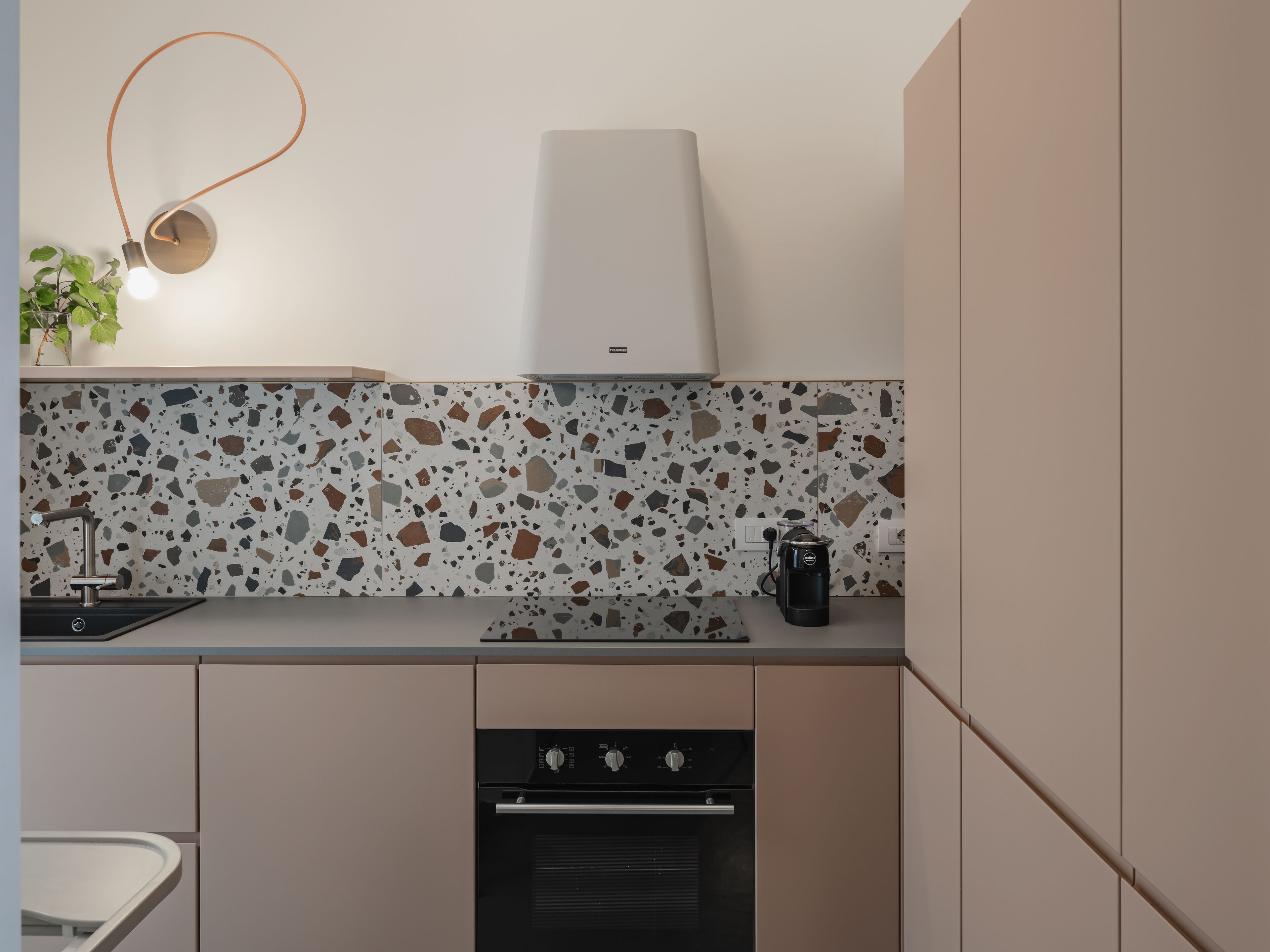 Una cocina moderna con una encimera, cafetera y horno empotrado.