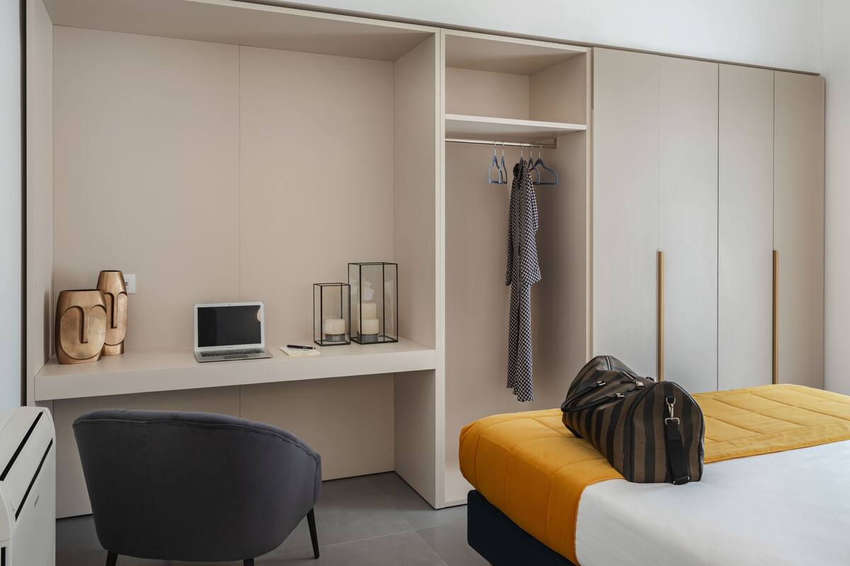 A modern bedroom with a bed, a desk, and a wardrobe.