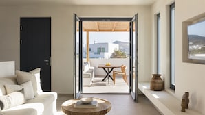 Ein modernes Wohnzimmer mit einer Couch, einem Couchtisch und Blick auf eine Terrasse mit Tisch und Stühlen.