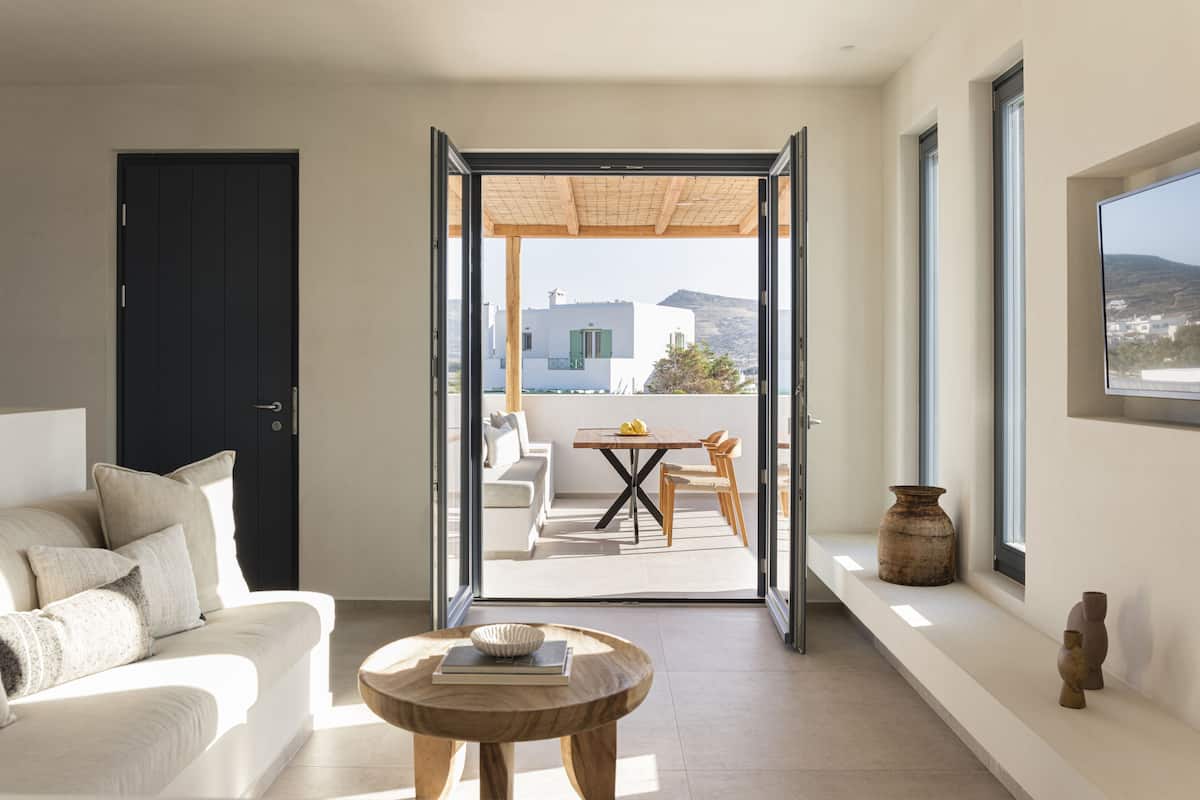 A modern living room with a sofa, a coffee table, and a view of an outdoor patio area with a table and chairs.