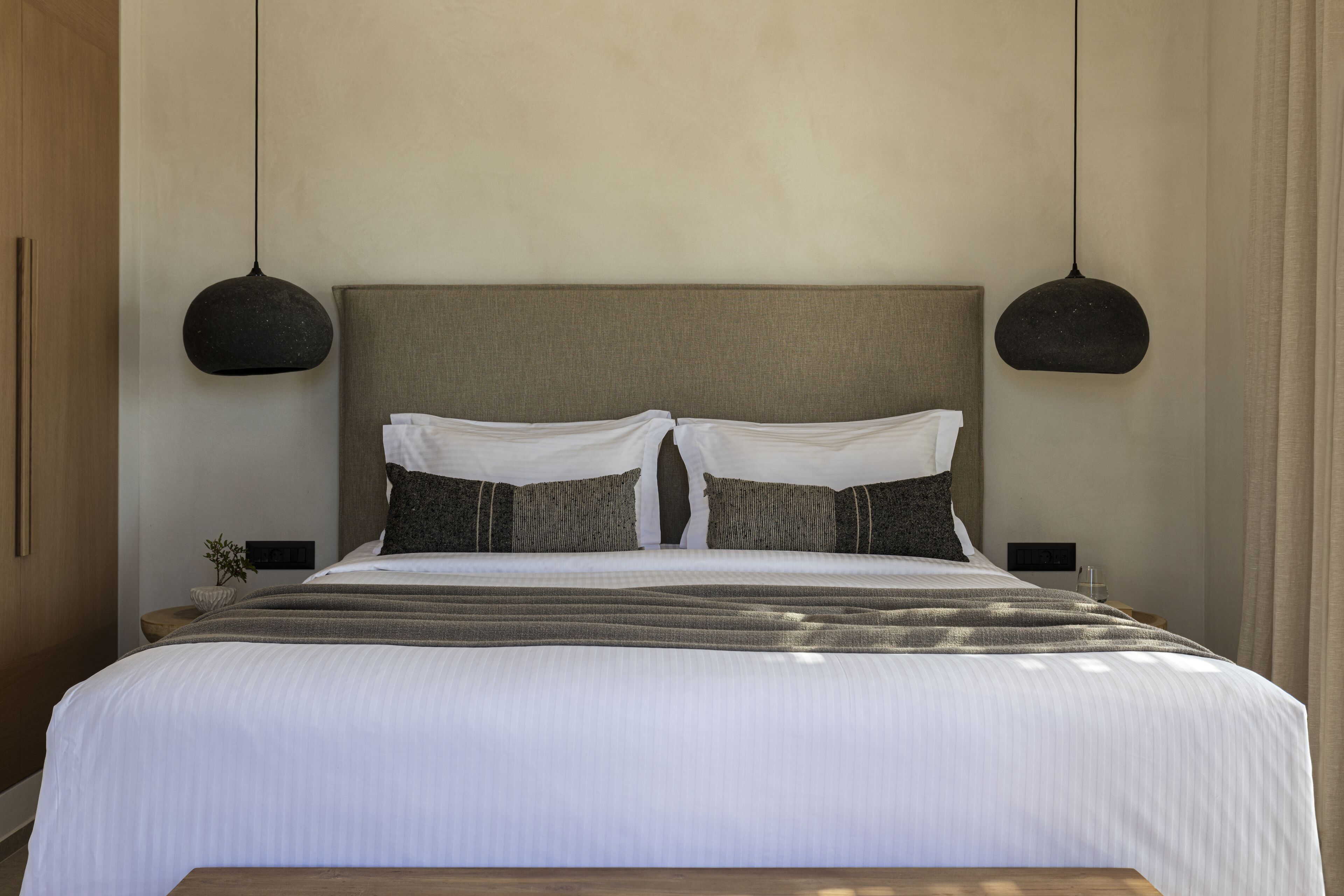 Un dormitorio moderno con una cama grande, dos mesitas de noche y lámparas colgantes.