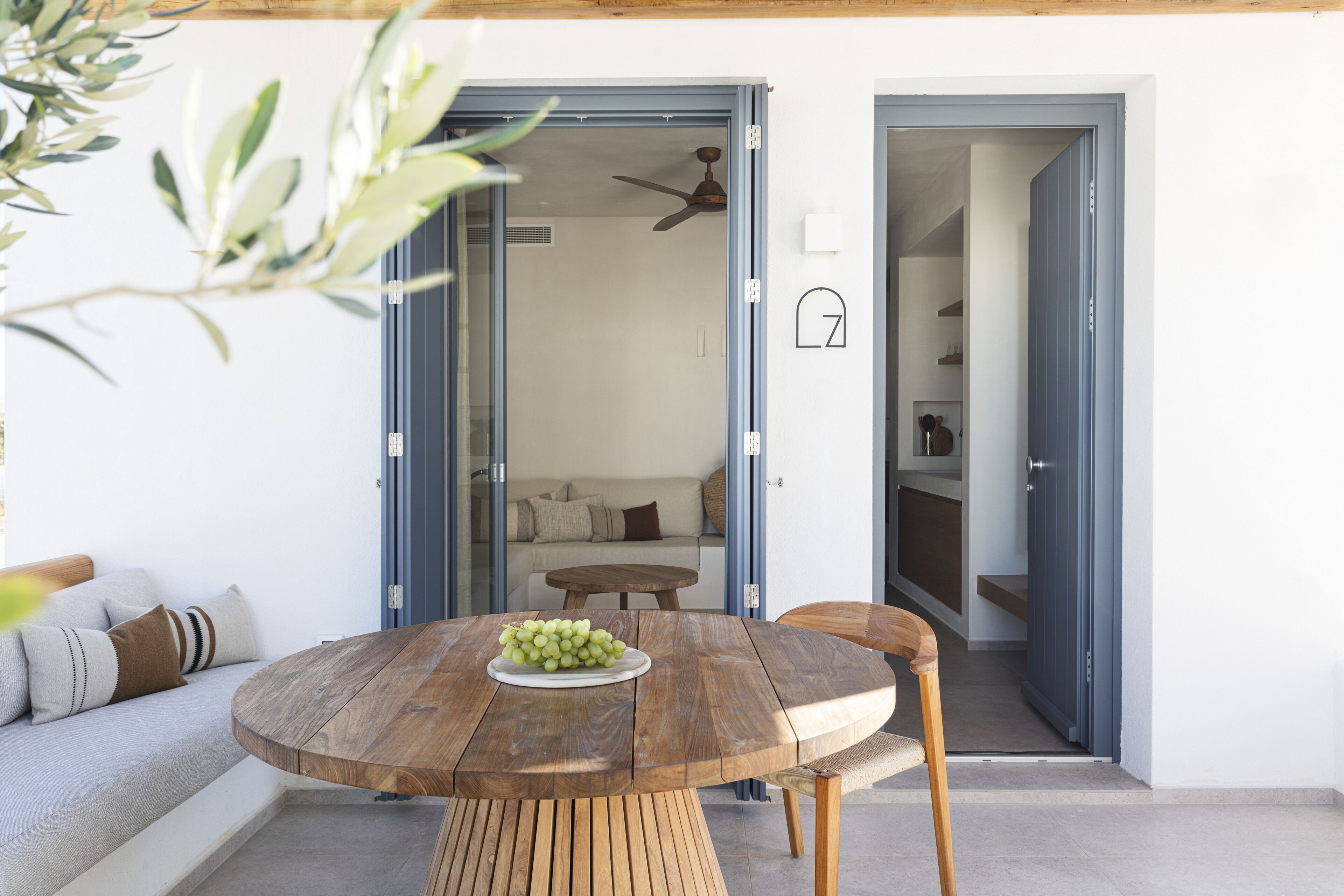 Un espacio habitable de concepto abierto con una mesa de comedor de madera, un sofá y una cocina visible a través de una puerta abierta.