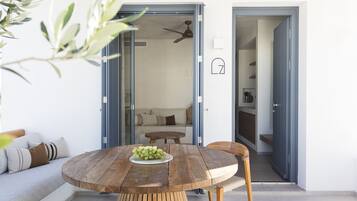 Un espacio habitable de concepto abierto con una mesa de comedor de madera, un sofá y una cocina visible a través de una puerta abierta.