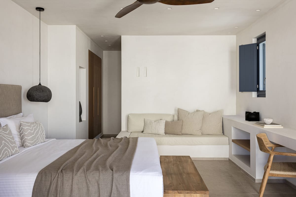 A modern bedroom with a bed, bedside table, and a desk with a chair.