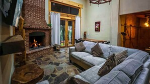 Una sala acogedora con chimenea de piedra, un sofá confortable y una mesa de madera.