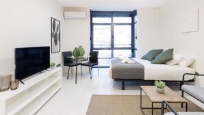 A modern, well-lit living room with a flat-screen TV, a sofa, a coffee table, and a dining area with chairs and a small table. - La Latina studio in the heart of Madrid (Madrid)
