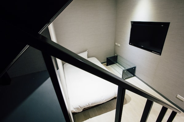 Un dormitorio moderno con cama, mesita de noche y televisor montado.