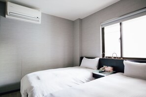 Une chambre d’hôtel avec deux lits, une fenêtre et un appareil de climatisation.