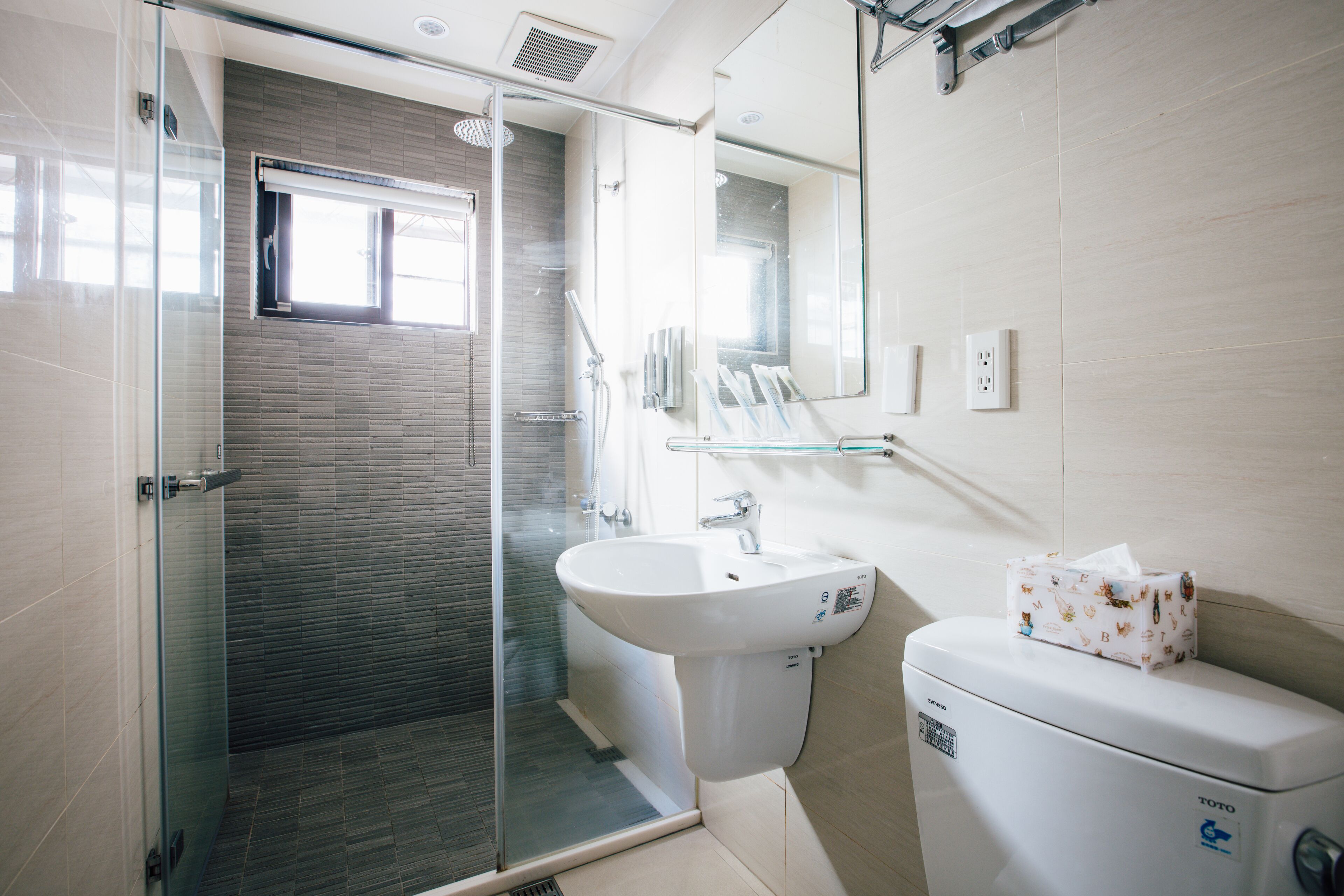 Un baño moderno con cabina de ducha de vidrio, un lavabo blanco y un inodoro.