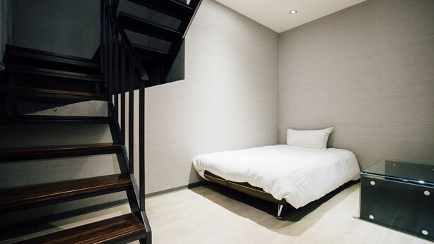 A modern bedroom with a bed, a glass table, and a wooden staircase. - Jiyuan APT (Taipei)