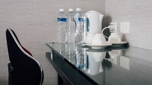 A hotel room with a glass-top table, water bottles, a coffee maker, and a guitar. - Jiyuan APT (Taipei)
