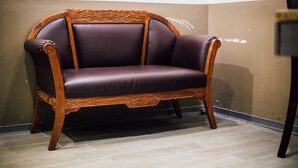 A wooden sofa with a cushioned seat and backrest, positioned against a wall with a tiled floor. - Jiyuan APT (Taipei)