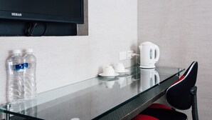 A hotel room with a glass table, two water bottles, a kettle, and a chair. - Jiyuan APT (Taipei)