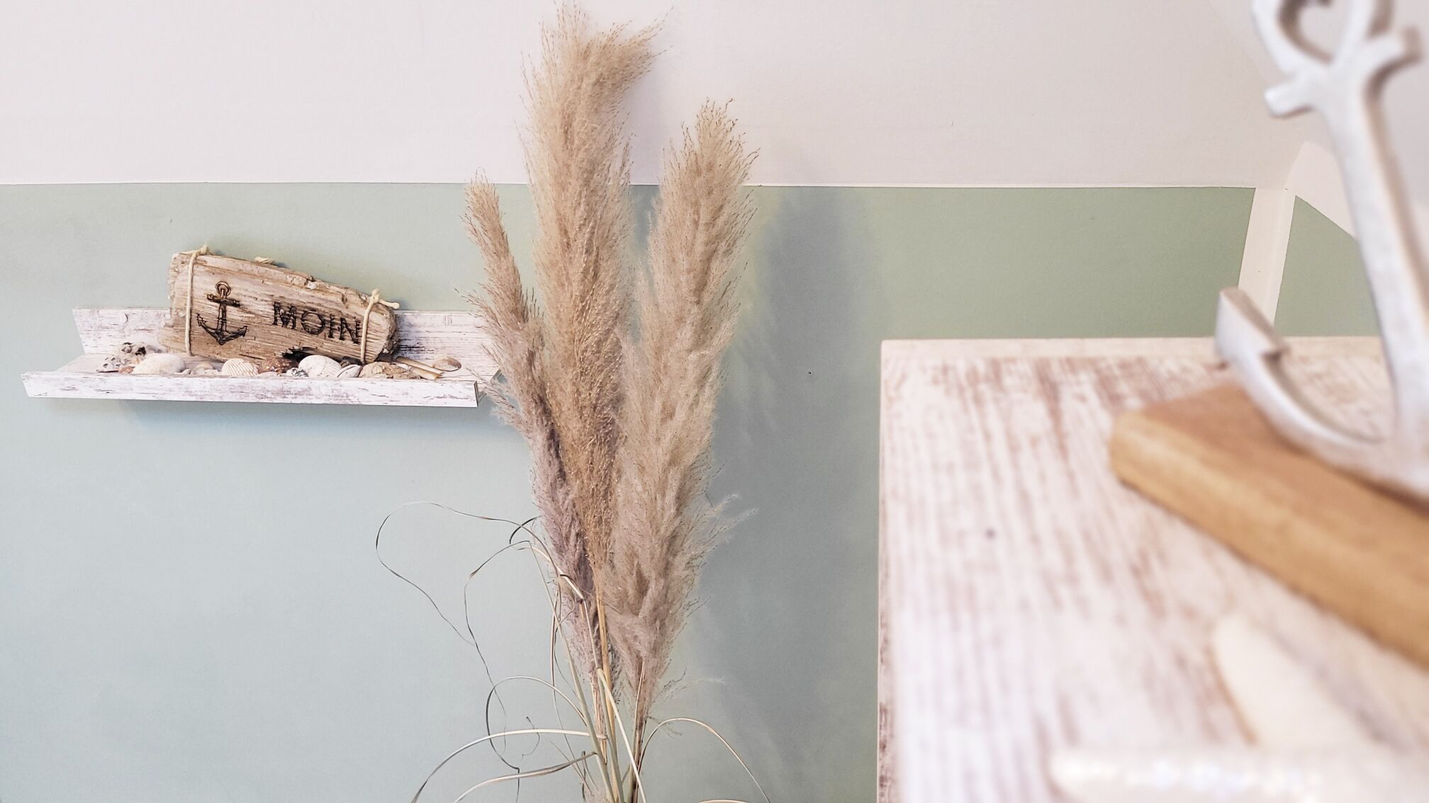 A rustic wooden shelf with a sign that reads "MOM" and pampas grass.