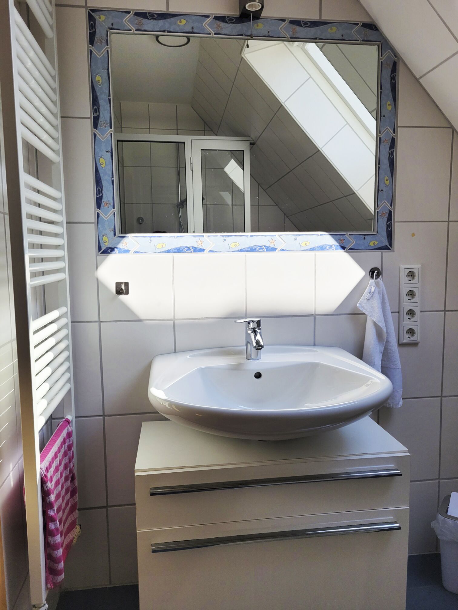 Un baño con un lavamanos blanco, un espejo con un marco decorativo y un perchero para toallas.