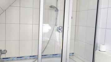 Aseo con cabina de ducha con puerta de vidrio, inodoro y bañera con un detalle de azulejos decorativos.