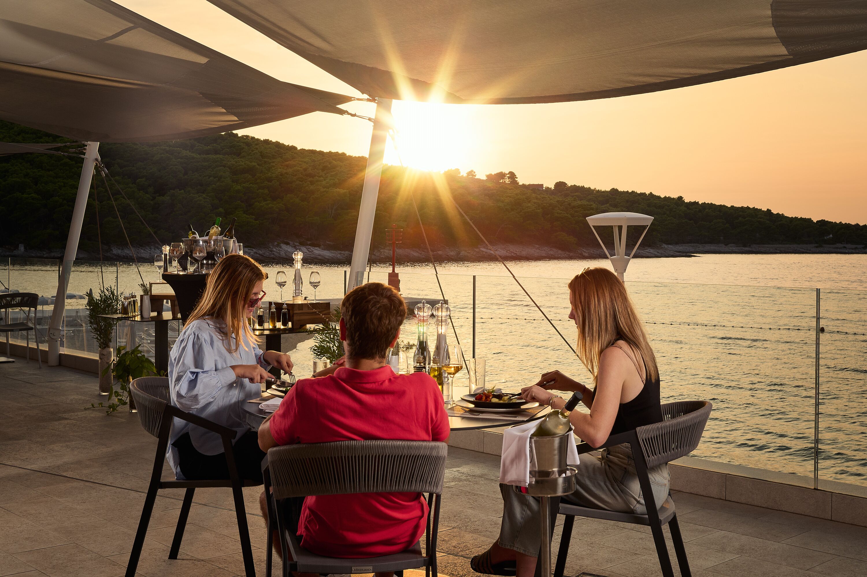 Una terrazza con un tavolo apparecchiato per mangiare, con vista su un corpo d'acqua e un paesaggio collinare.