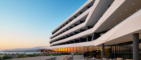 Un edificio moderno con varios balcones, mobiliario exterior y vistas al mar.
