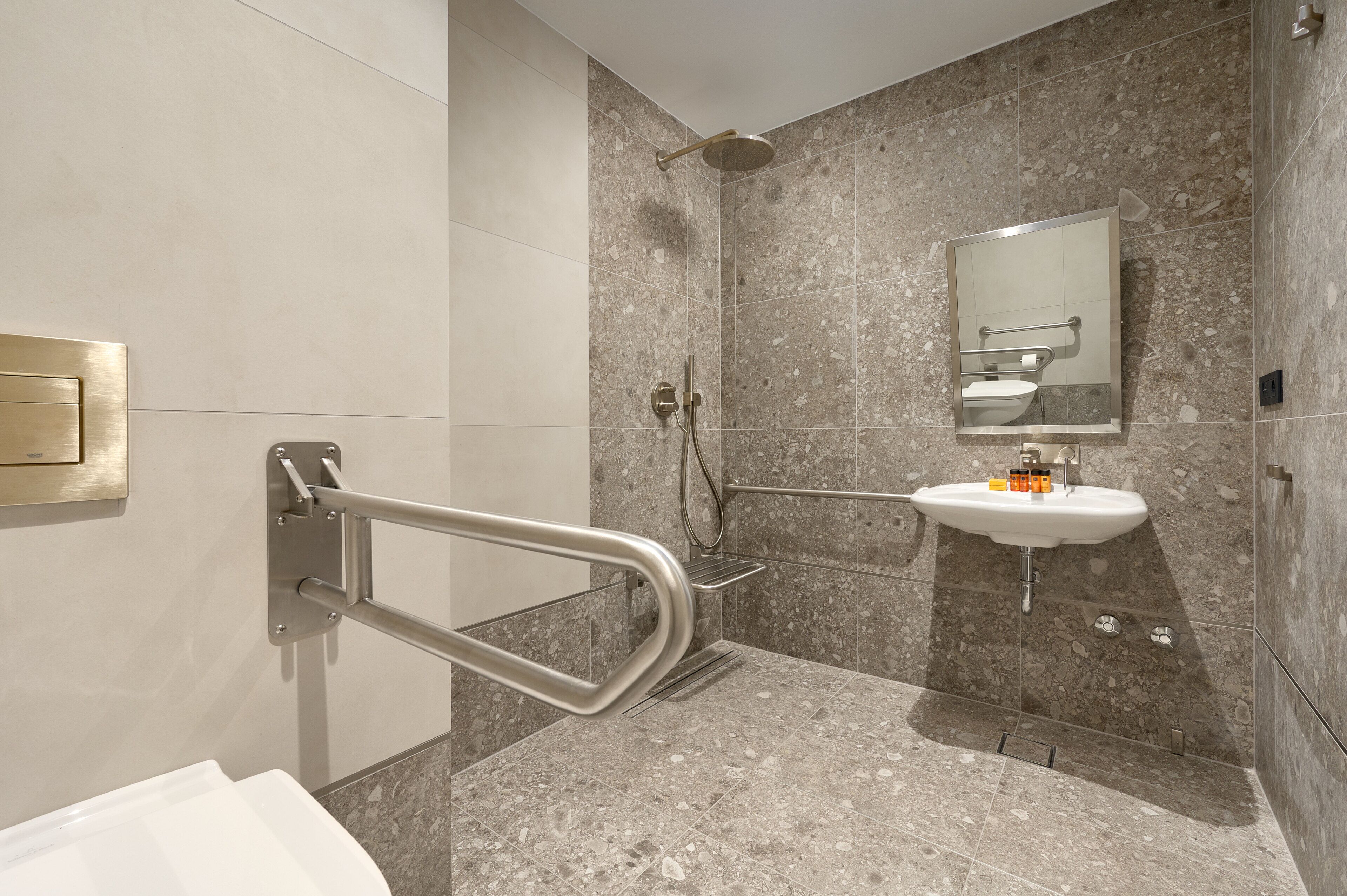 Un baño moderno con pasamanos, un lavabo y una ducha.