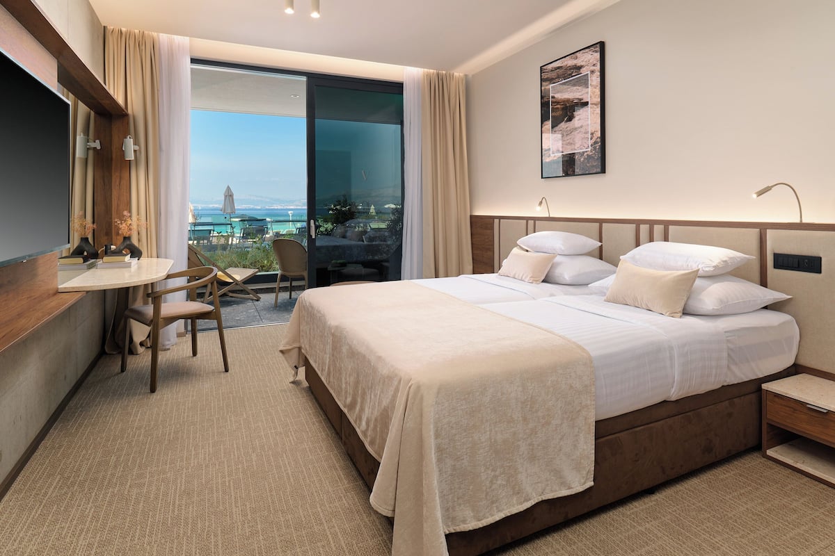 A hotel room with a large bed, a desk, and a view of the ocean.