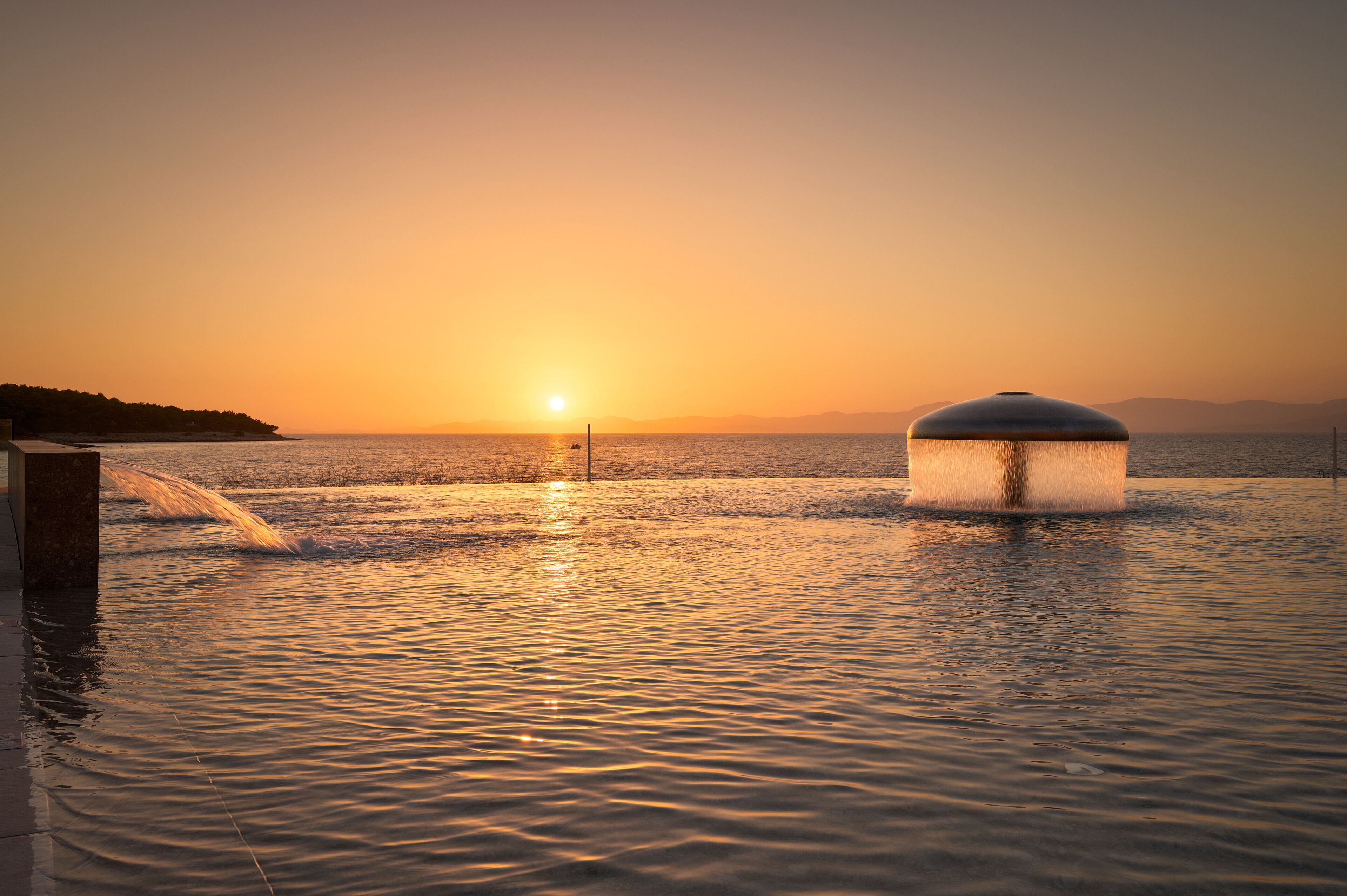 A waterfront scene with a large water feature and a sunset.