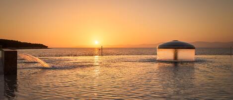A waterfront scene with a large water feature and a sunset.