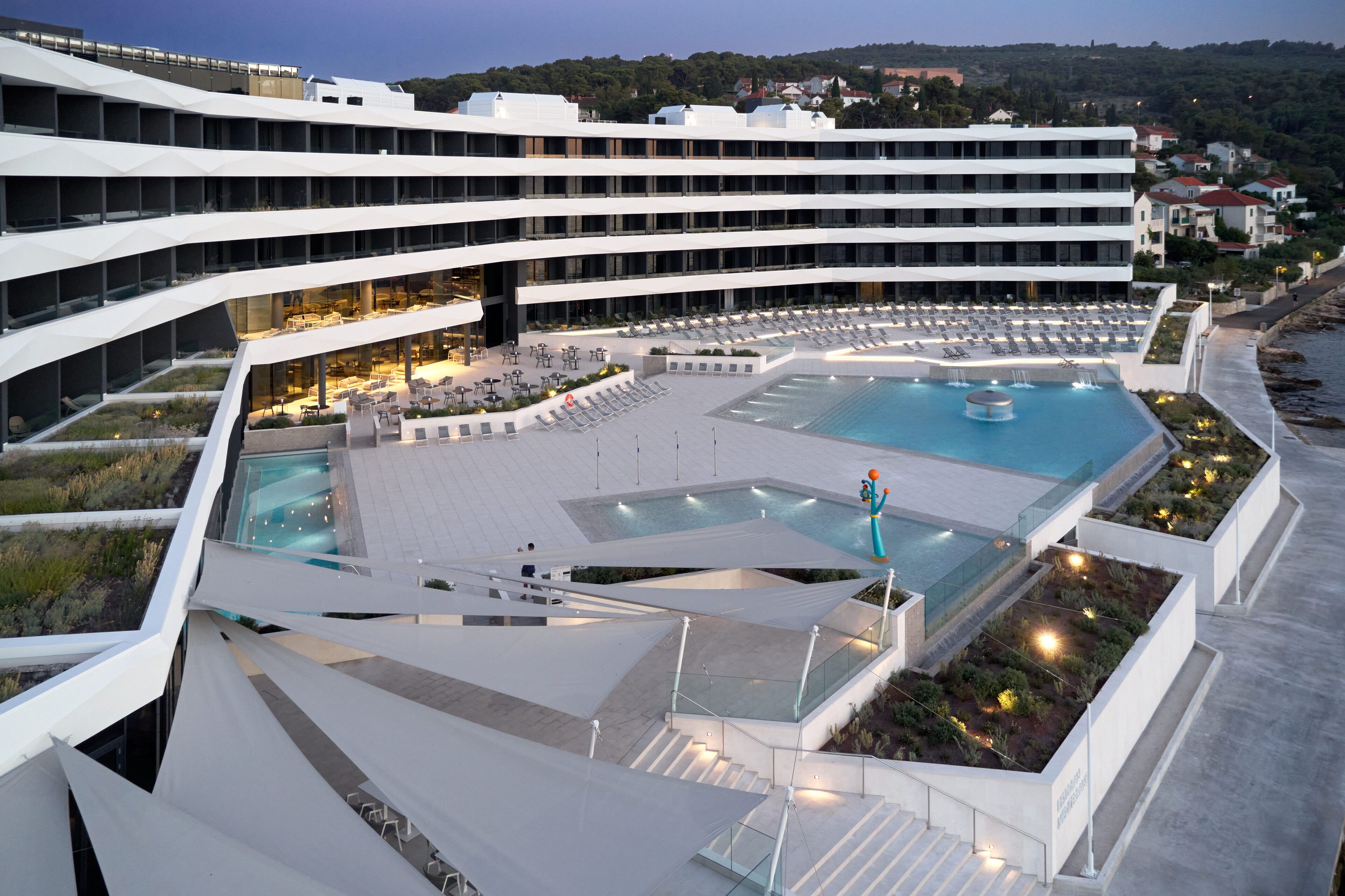 Un hôtel moderne à plusieurs étages, doté d’une piscine sur le toit et d’une terrasse aménagée.