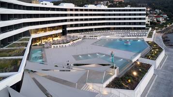 A modern hotel with multiple floors, a rooftop pool area, and a landscaped terrace.