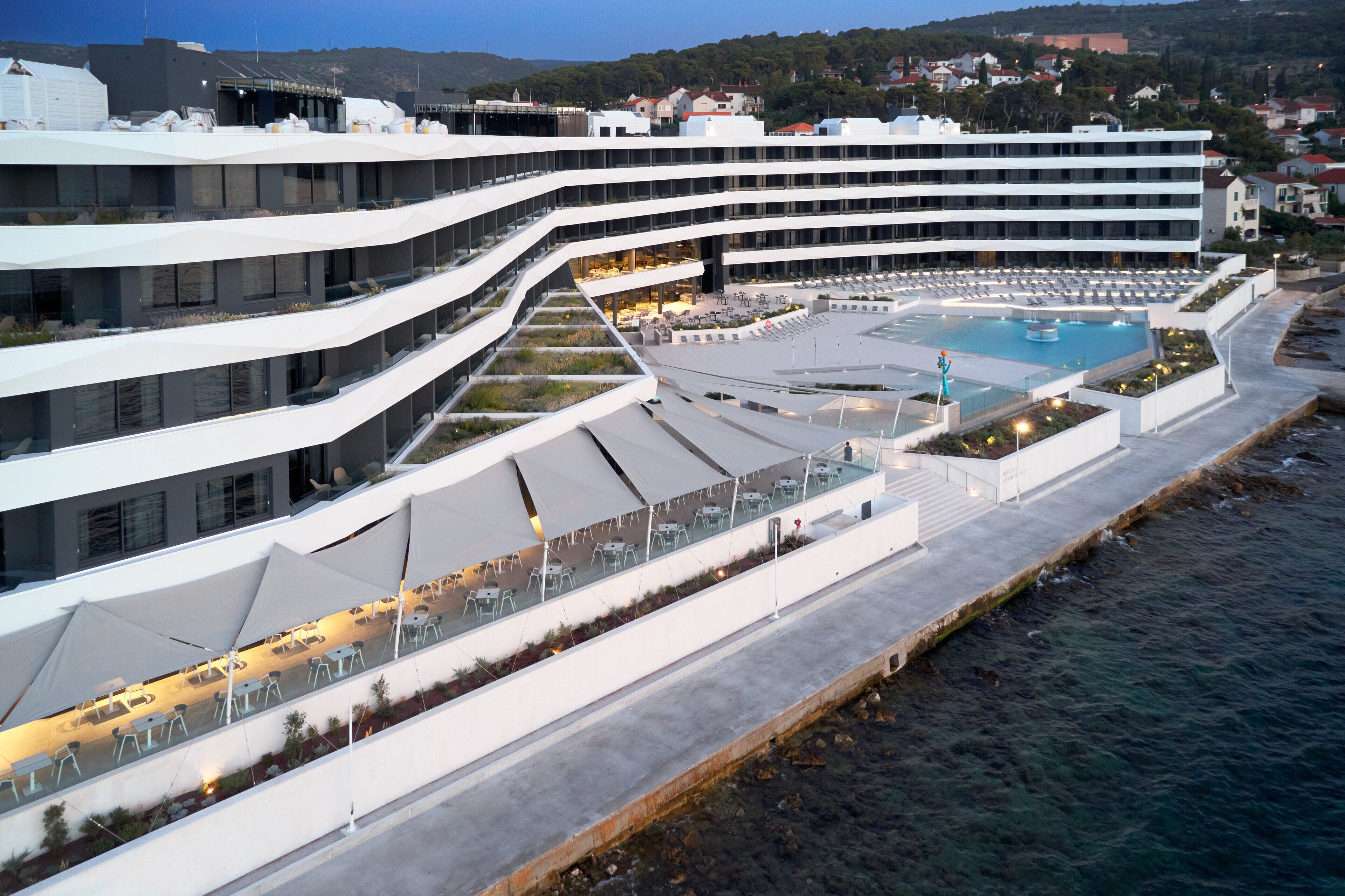 Un hôtel moderne doté d’une piscine, d’un espace extérieur aménagé et offrant une vue sur le bord de l’eau.