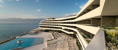 Ett modernt hotell med pool, utomhusservering och utsikt över havet.