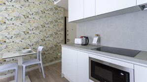 Eine kleine Küchenzeile mit weißer Arbeitsplatte, einem Toaster, einem Wasserkocher und einer Mikrowelle.