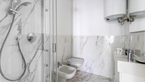 Ein modernes Badezimmer mit einer Duschkabine, Toilette, Bidet und Waschbecken mit Spiegel.