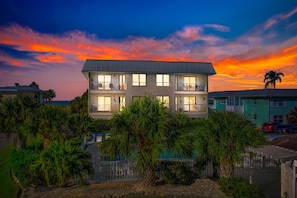 A two-story building with balconies, surrounded by palm trees and a swimming pool. - Anna Maria Island Beach Waves (Bradenton Beach)