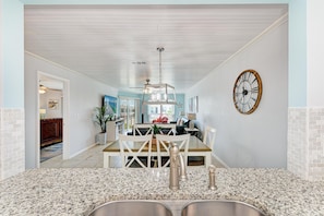 A modern kitchen with granite countertops, stainless steel appliances, and a dining area with a wooden table and chairs. - Anna Maria Island Beach Waves (Bradenton Beach)
