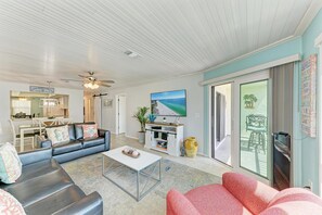 A spacious living room with a ceiling fan, a flat-screen TV mounted on the wall, and a dining area with a table and chairs. - Anna Maria Island Beach Waves (Bradenton Beach)