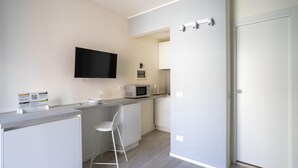A modern kitchen with a flat-screen TV, a microwave, and a bar stool. - Italianway - The B Village Superior - 40 (Milan)