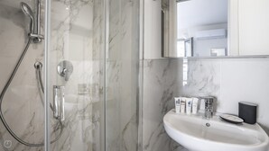 A bathroom with a glass-enclosed shower, a white sink, and toiletries. - Italianway - The B Village Superior - 40 (Milan)