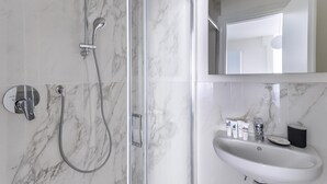 Ein modernes Badezimmer mit einer gläsernen Duschkabine, einem wandmontierten Waschbecken und einem großen Spiegel.