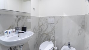 Ein Badezimmer mit Waschbecken, Toilette und Marmorwänden.