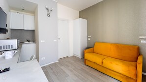 A modern living space with a kitchen, a sofa, and a wall-mounted light fixture. - Italianway - The B Village Business - 30 (Milan)