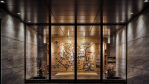 A modern hotel entrance with a glass door, a wooden interior wall with maps and illustrations, and a small indoor garden. - OMO3 Tokyo Akasaka by Hoshino Resorts (Tokyo)