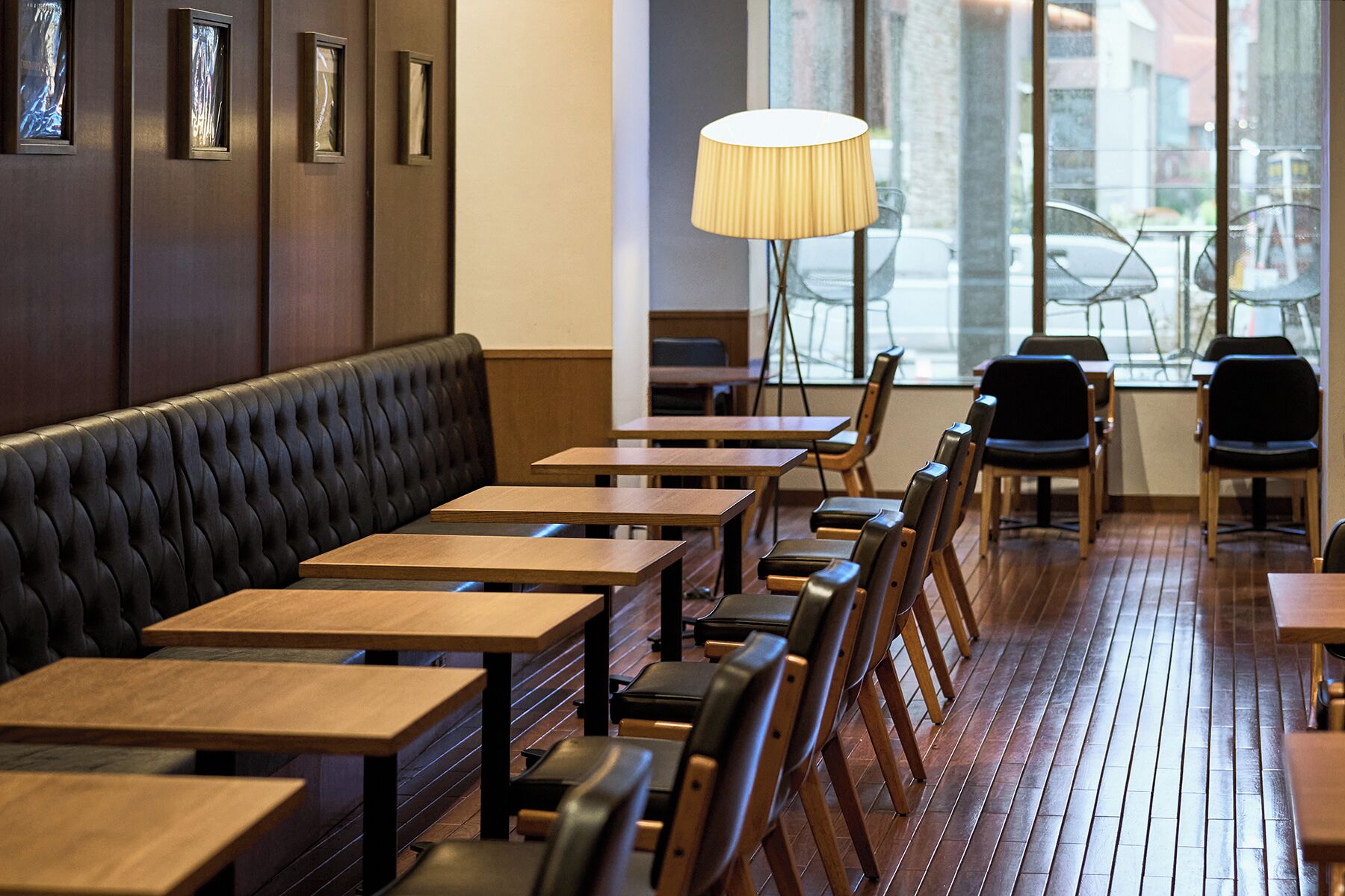 A restaurant interior with a long wooden bench, multiple tables, and chairs.